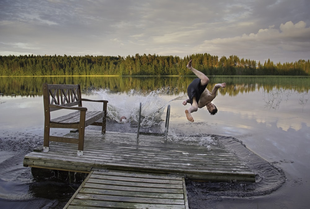 man in black tank top and black shorts jumping on water during daytime