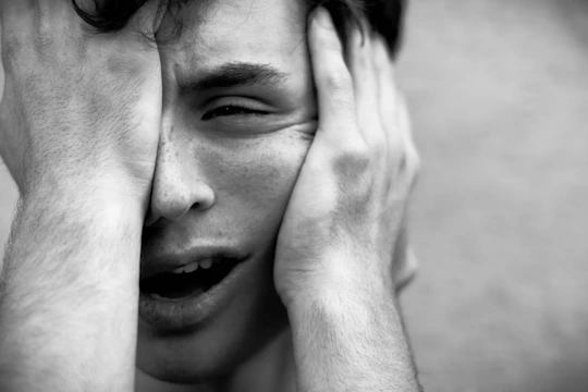 Close-up of a person holding their chest with a worried expression, symbolizing physical anxiety symptoms.