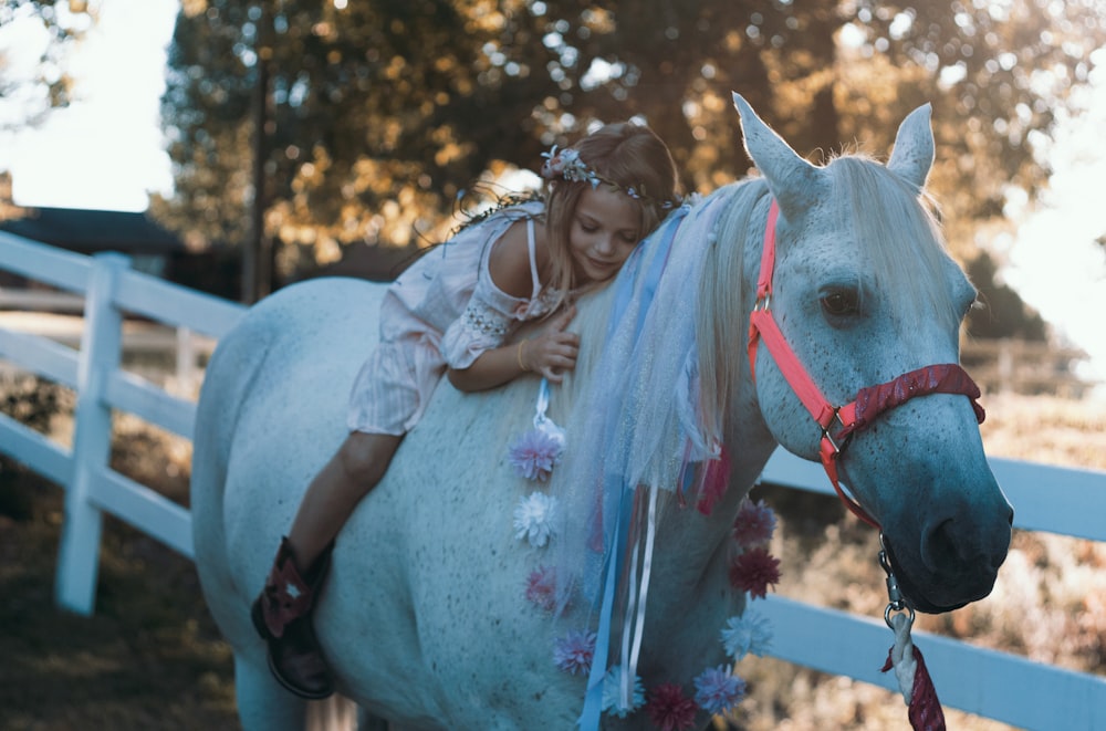 Mädchen reitet tagsüber auf weißem Pferd