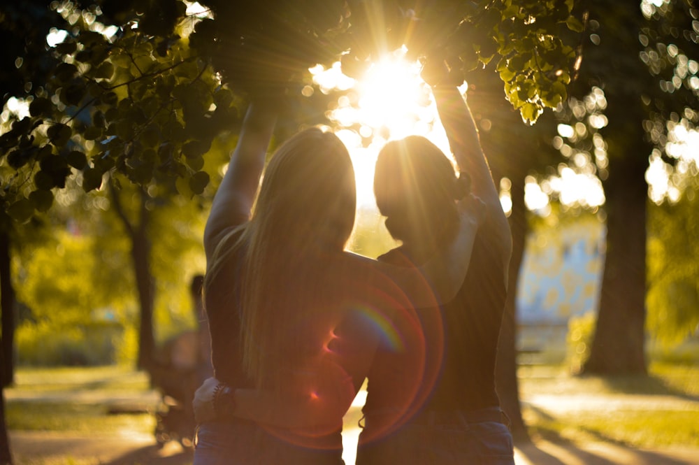 silhouette photo of two woman pointing to the sky