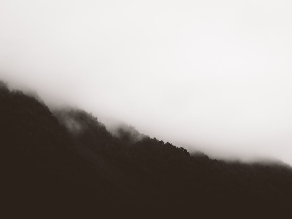 a black and white photo of a foggy mountain