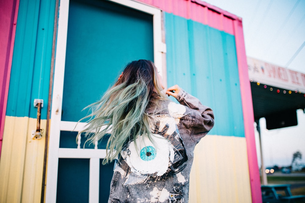 woman wearing grey denim jacket standing beside intermodal container