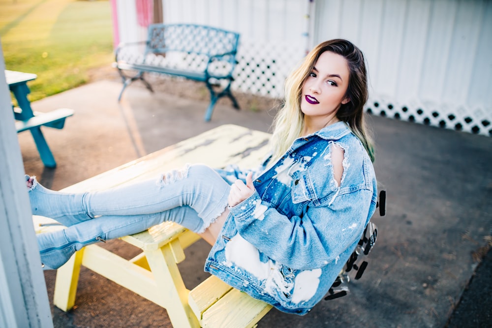 smiling woman sitting on yellow picnic table during daytime