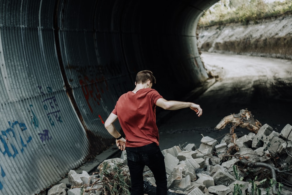 man in red shirt and black pants standing on CMU blocks on tunnel