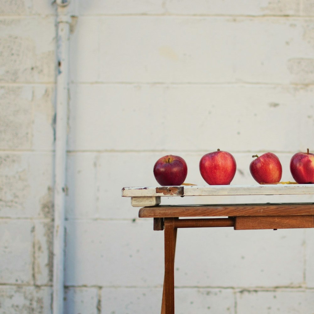 manzanas rojas sobre tabla de madera blanca