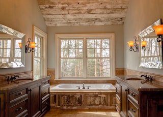 comfort room with white bathtub and brown wooden cabinets