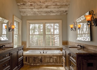 comfort room with white bathtub and brown wooden cabinets