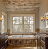 comfort room with white bathtub and brown wooden cabinets