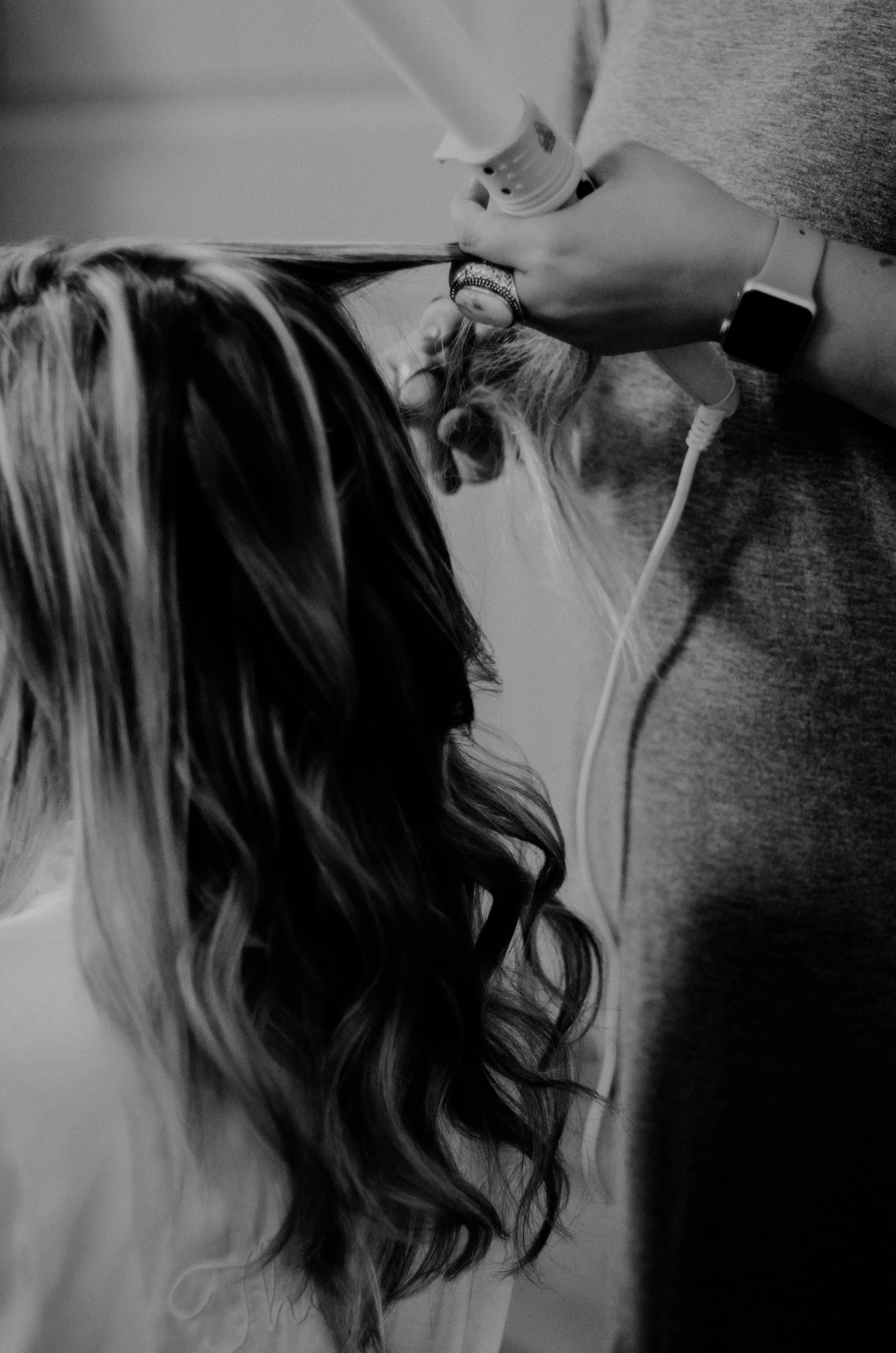 Professional hair styling session with curling iron creating elegant waves
