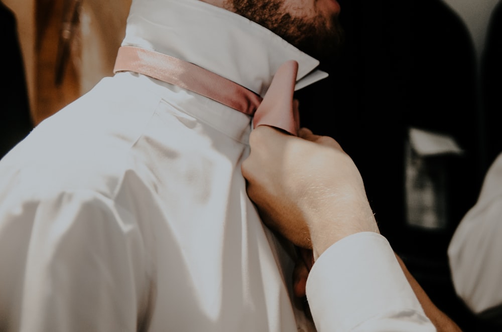um close up de uma pessoa amarrando uma gravata