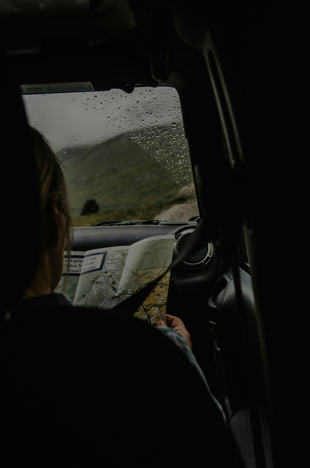 person sitting on front passenger seat holding map