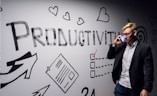 man holding smartphone looking at productivity wall decor