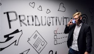 man holding smartphone looking at productivity wall decor