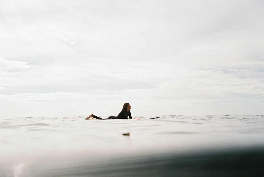 Mujer acostada en la tabla de surf en el cuerpo de agua