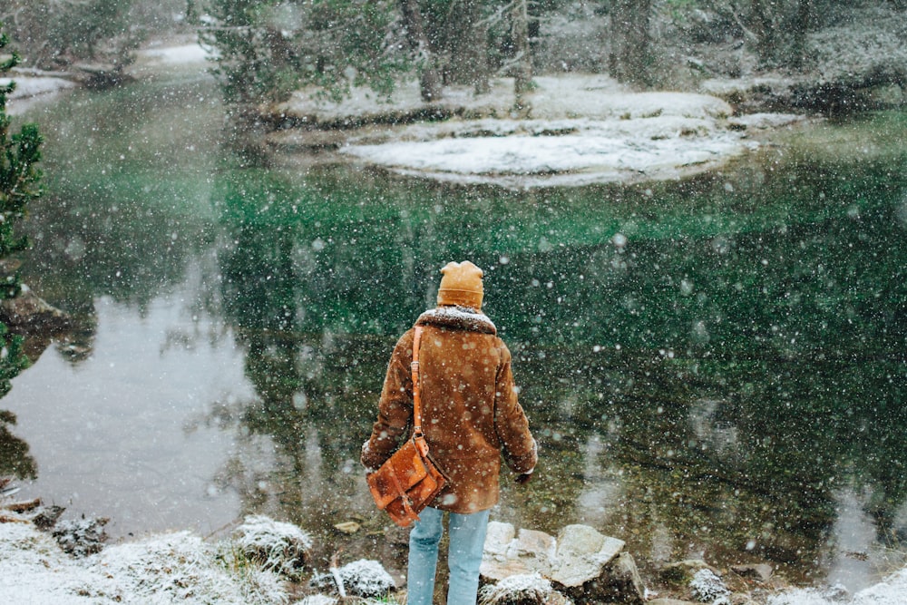 person wearing jacket standing near body of water