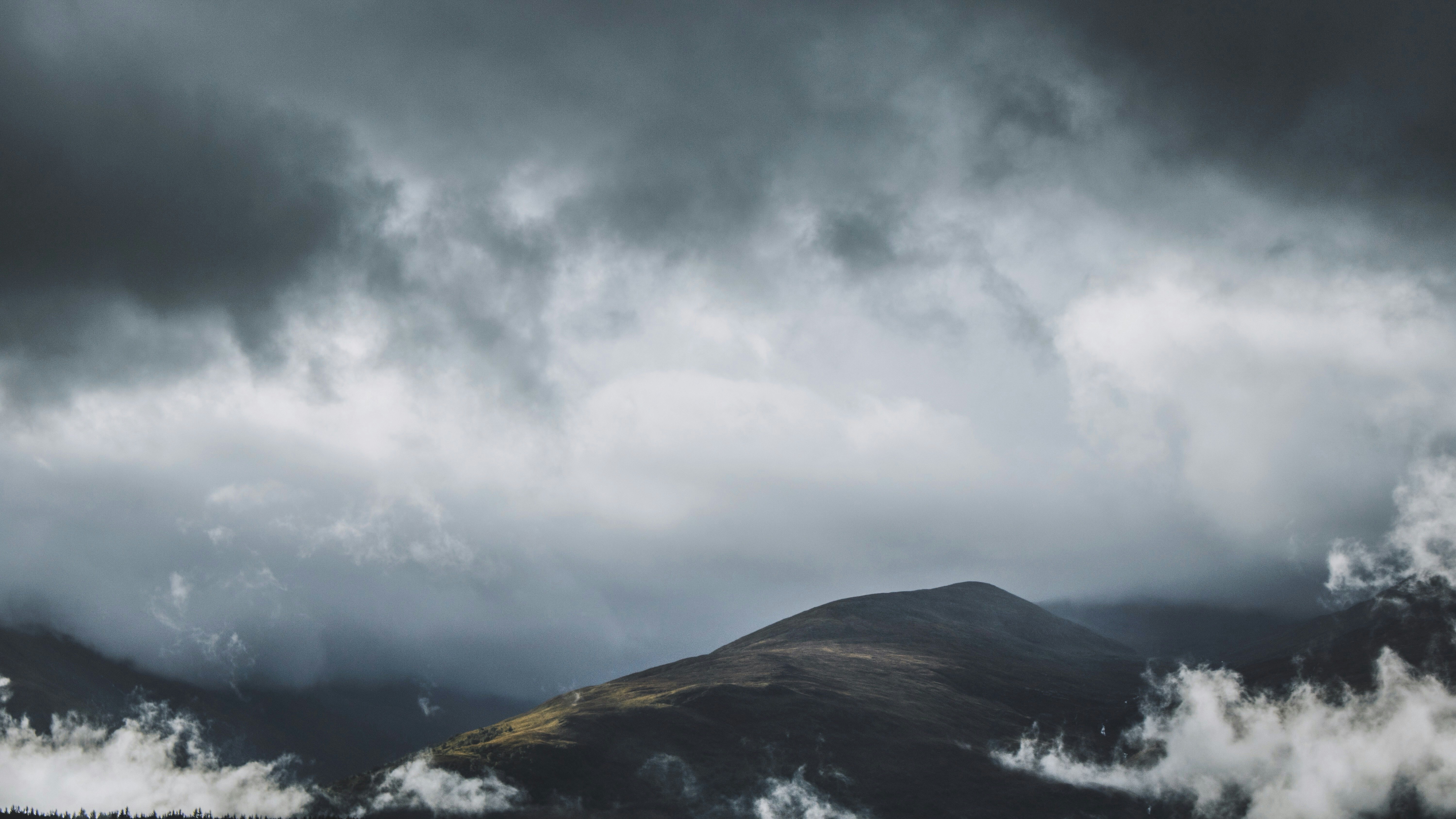 brown and black hill under cloudy sky during daytime