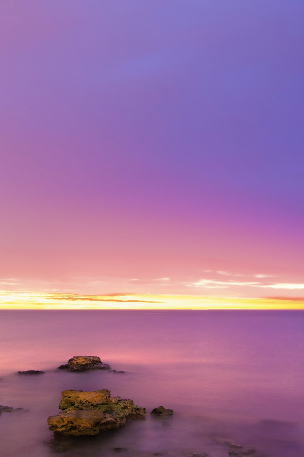 rock formation on body of water during sunrise