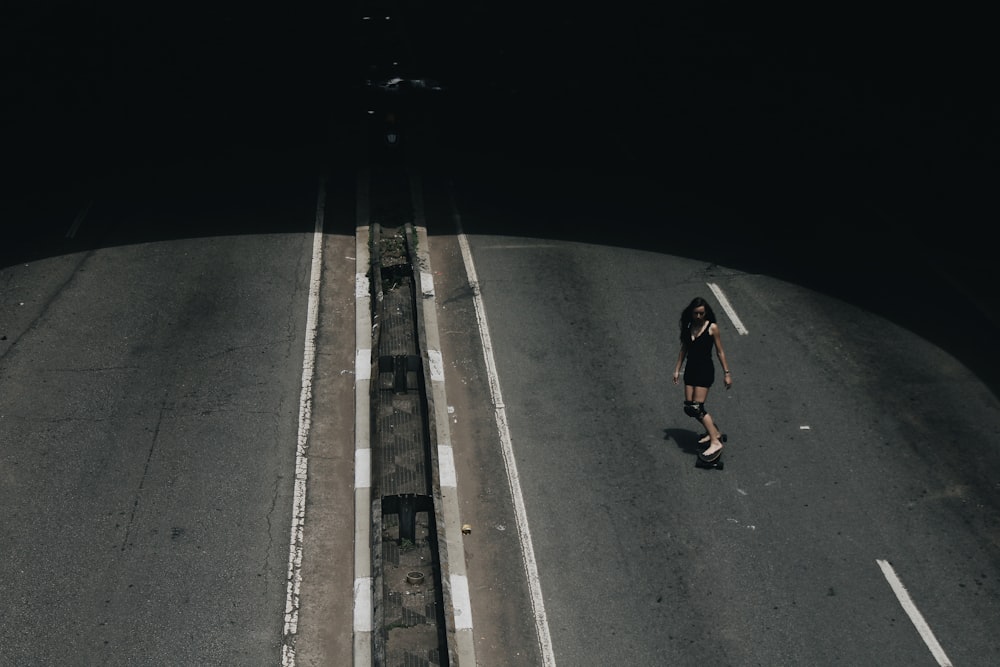 high angle photo of woman riding on skateboard passing road