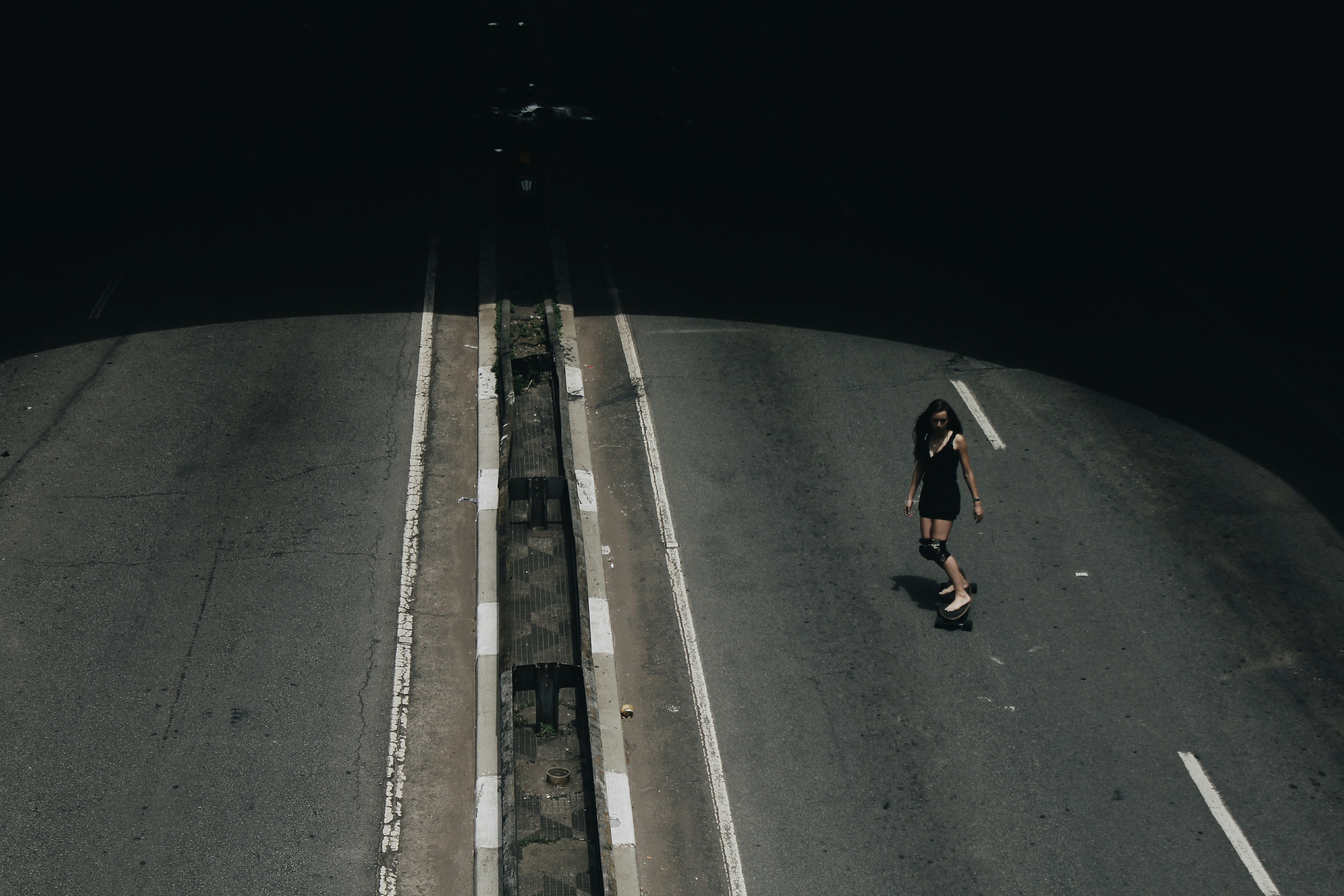 high angle photo of woman riding on skateboard passing road