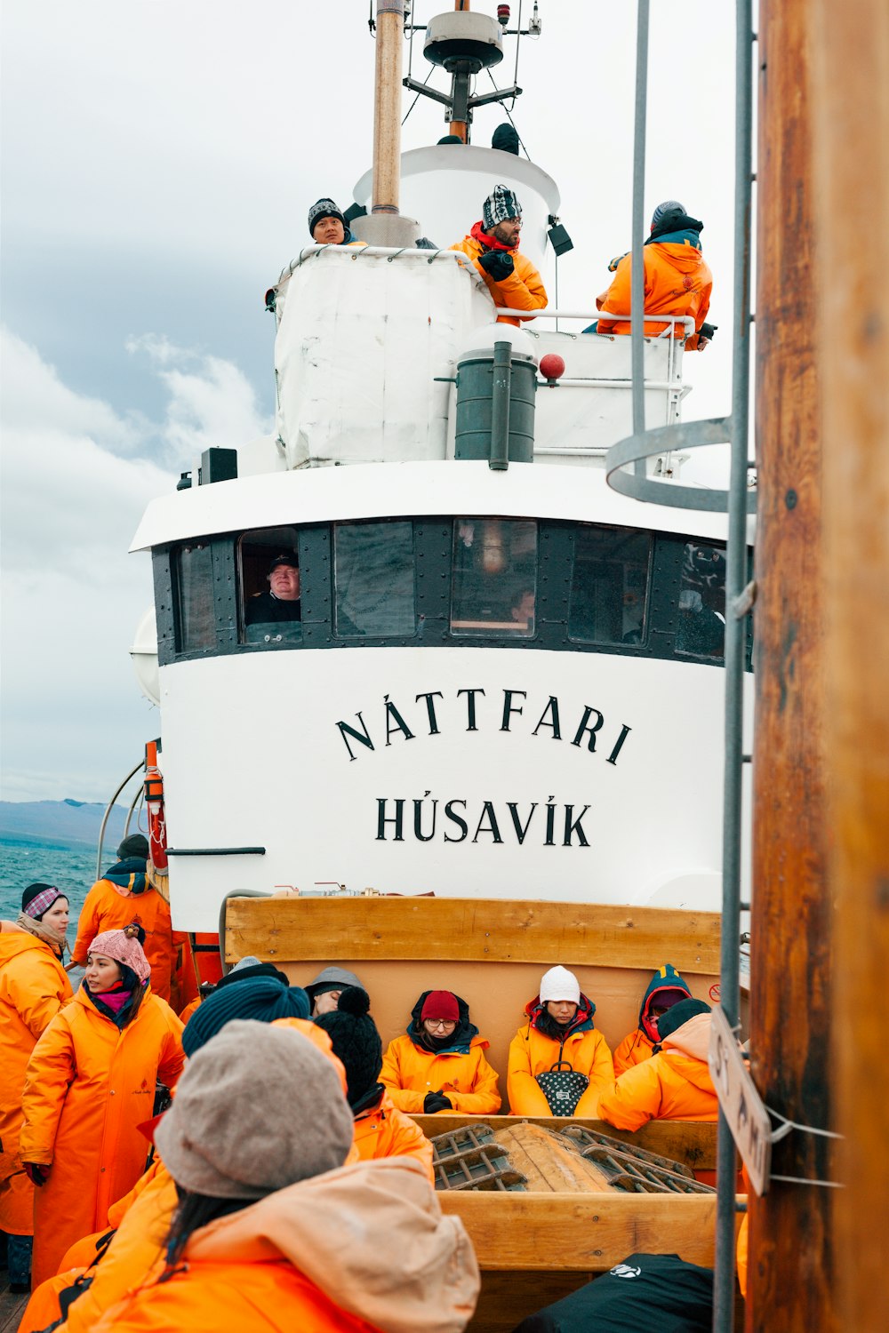 people on white Nattfari Husavik ship on body of water during cloudy weather