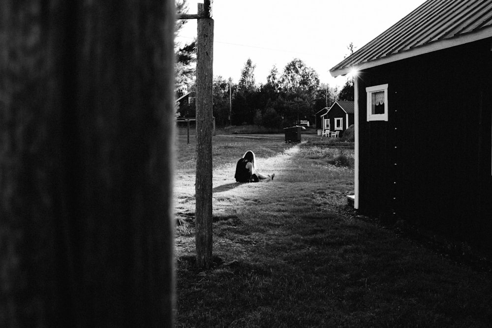 girl sitting on grass near house