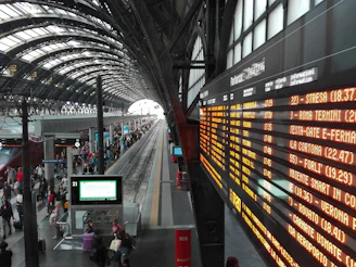 A happy traveler picking up a rental car at a busy Italian train station.