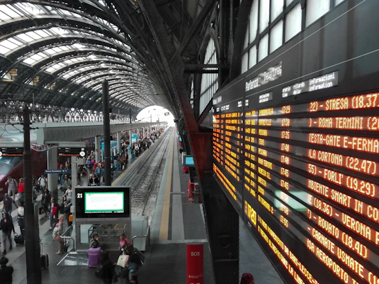 A happy traveler picking up a rental car at a busy Italian train station.
