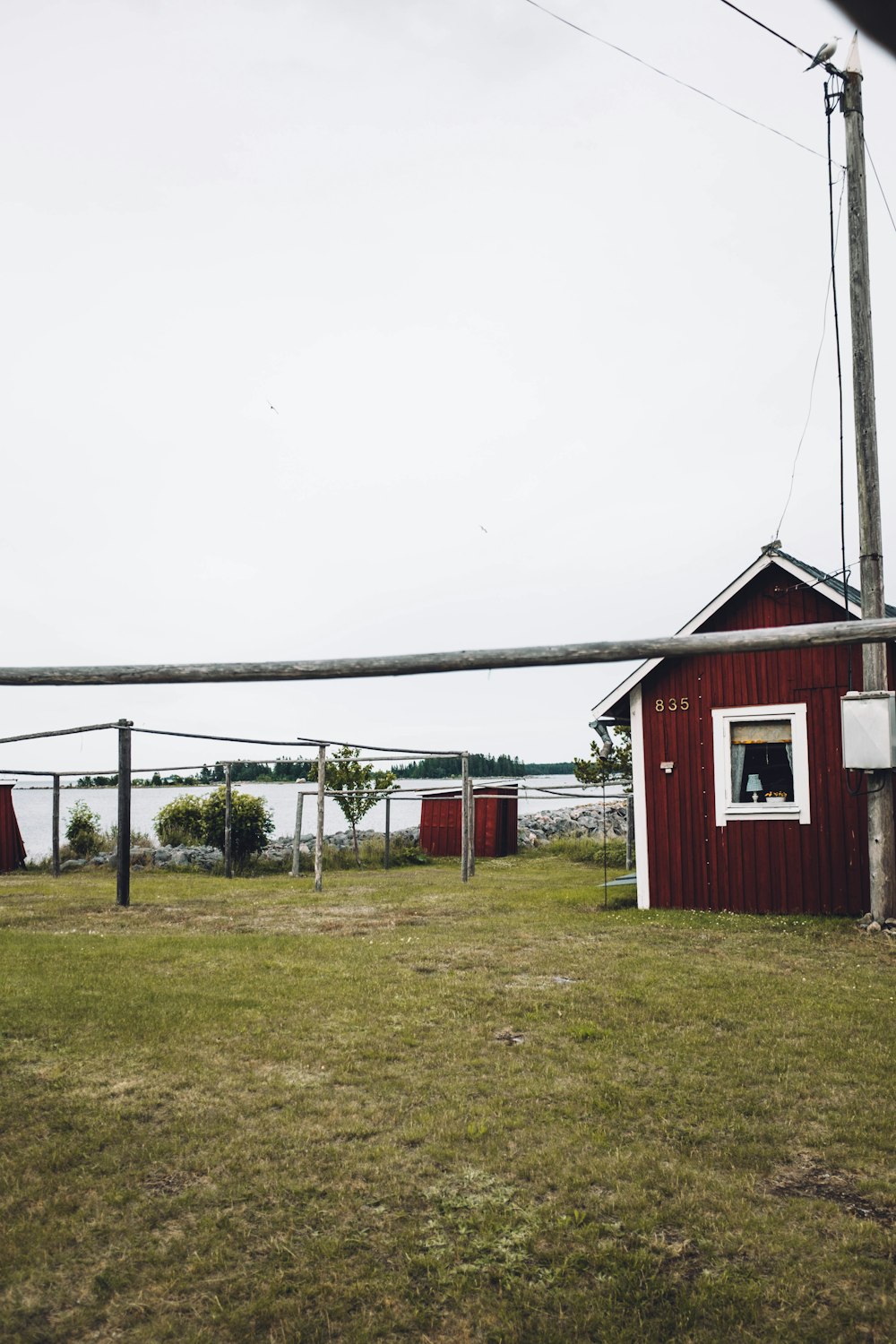 brown wooden shed near utility post under white sky