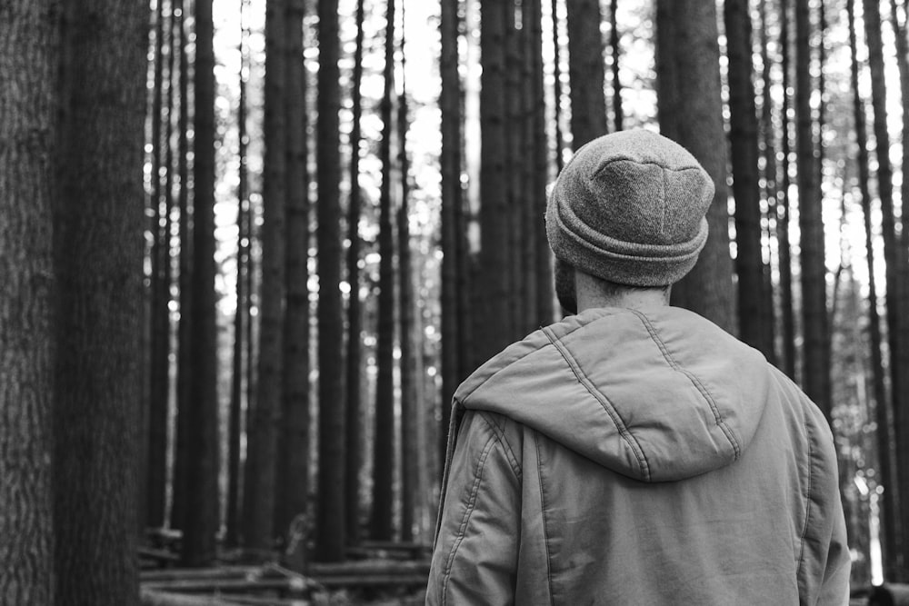 grayscale photo of a man looking at trees