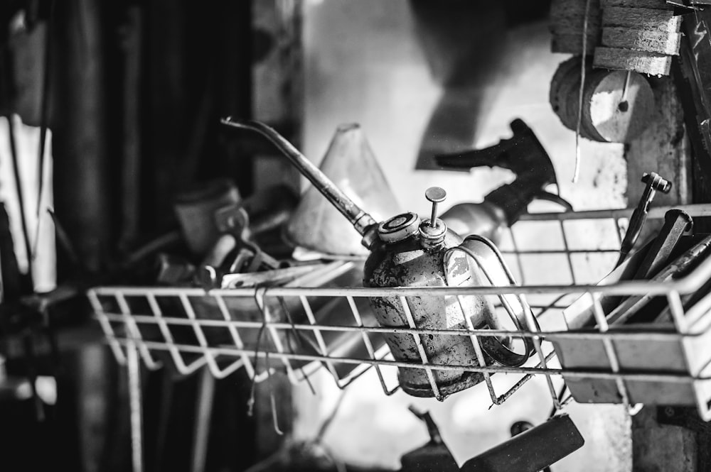 grayscale photography of oil can on wire rack