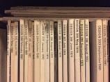 A collection of design journals is shelved vertically, with each journal's spine displaying the title 'DESIGN' followed by issue numbers and publication dates in chronological order from 1972 to 1986. The spines are mostly white or beige, with black print, and arranged with some minor wear visible on a few.