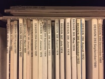 A collection of design journals is shelved vertically, with each journal's spine displaying the title 'DESIGN' followed by issue numbers and publication dates in chronological order from 1972 to 1986. The spines are mostly white or beige, with black print, and arranged with some minor wear visible on a few.