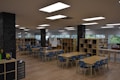 A spacious classroom or learning area filled with several wooden tables and blue chairs arranged neatly. Bookshelves line the room, filled with books and educational materials. The walls feature large windows that provide natural light. Chalkboards are visible on some pillars, displaying handwritten notes and drawings.