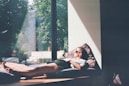 man lying on cushion beside glass window
