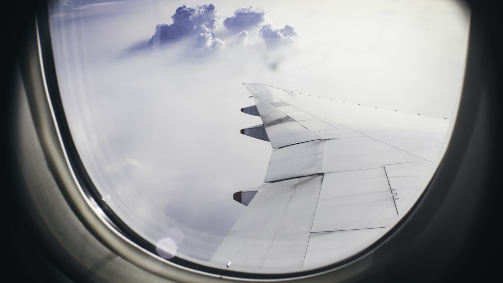 architectural photography of plane's wing above clouds during flight