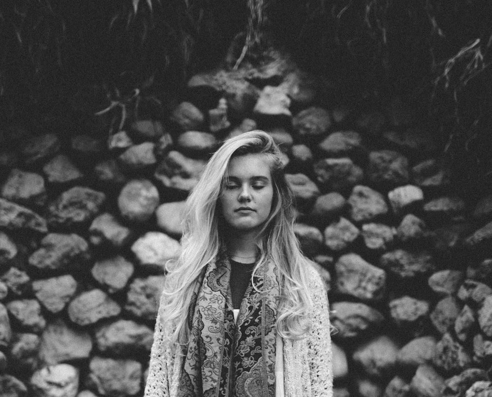 grayscale photography of woman standing near stones