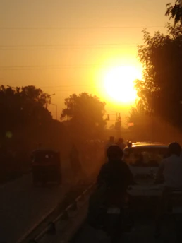 A golden-hued sunset casting long shadows over a bustling city street alive with vibrant local life.