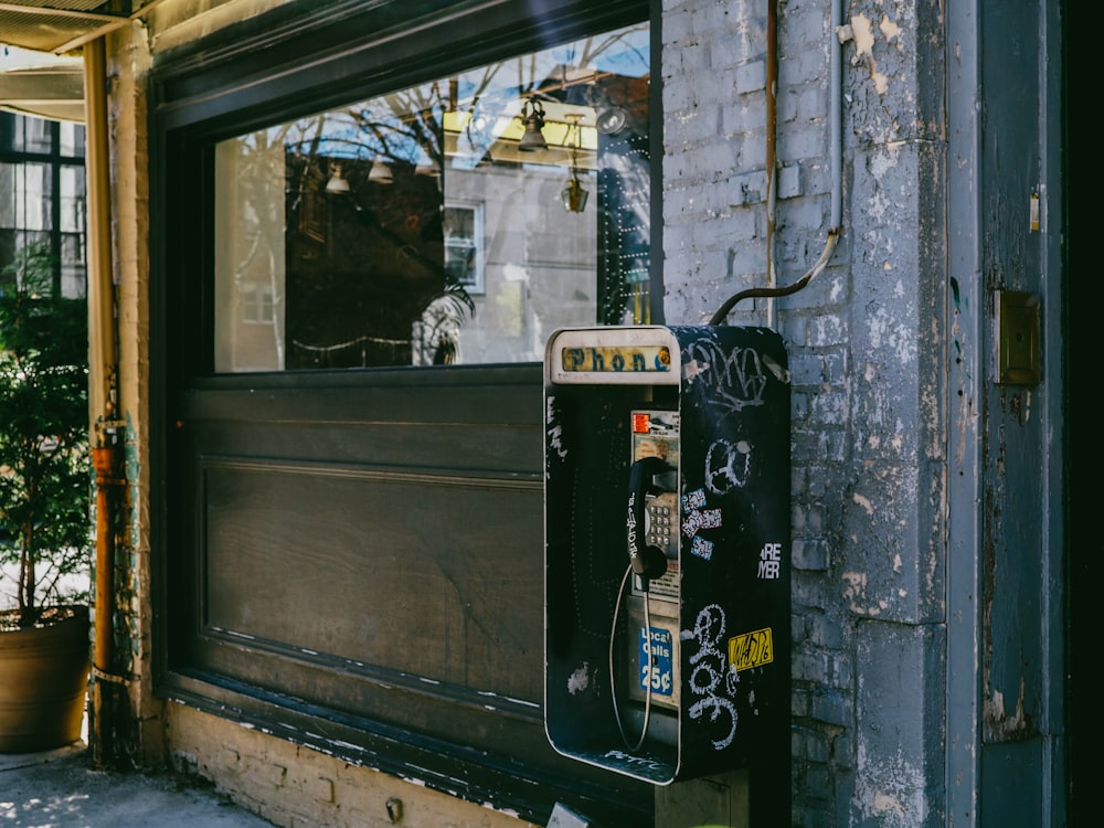 photo of black telephone booth near wall