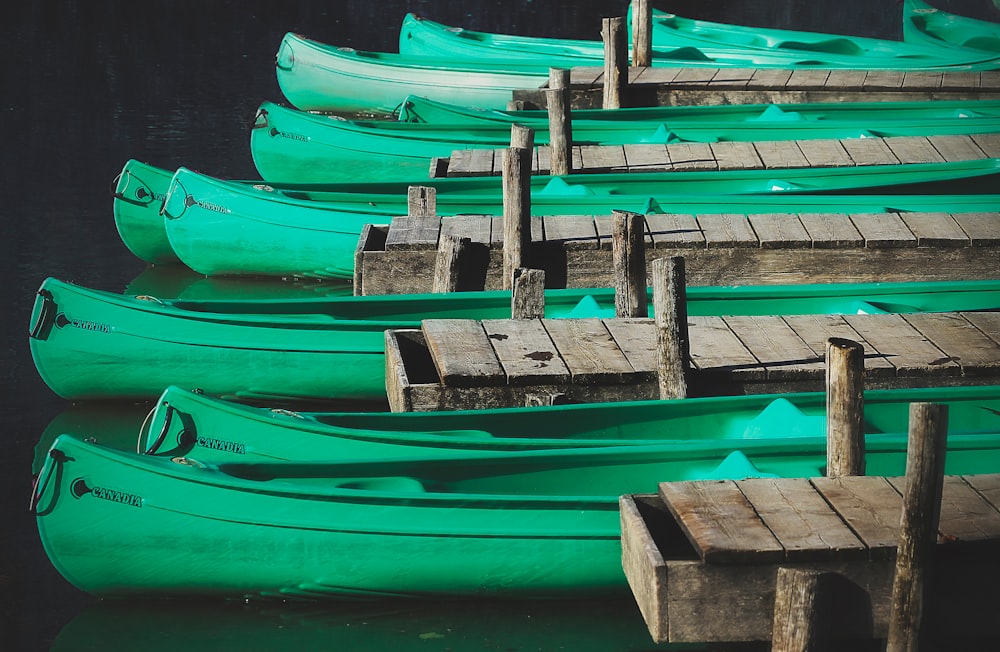 green wooden canoes docks near gray wooden sea docks