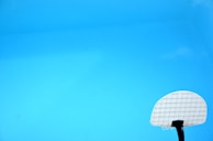 A swimming pool with clear blue water featuring a white basketball hoop in the lower right corner.