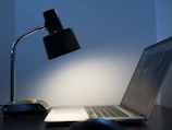 A sleek Nordic wooden table lamp illuminating a minimalist workspace.