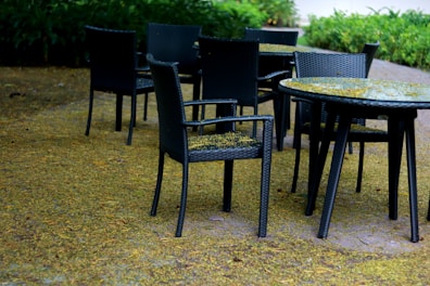 Outdoor hotel seating area with tables and chairs surrounded by greenery