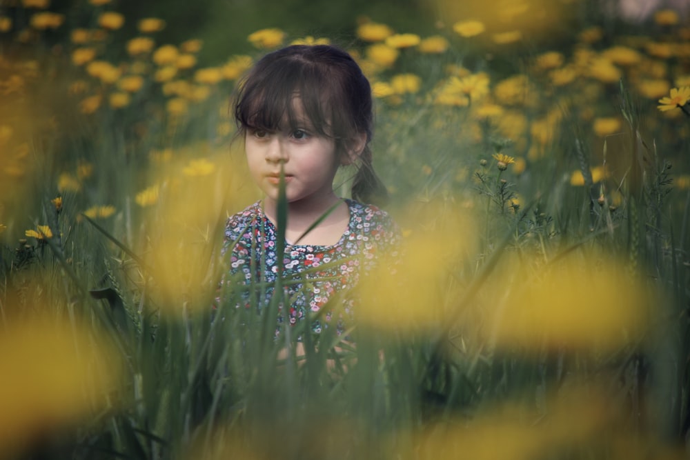 노란 꽃잎이 달린 꽃밭에 여러 가지 빛깔의 탑을 입고 있는 소녀