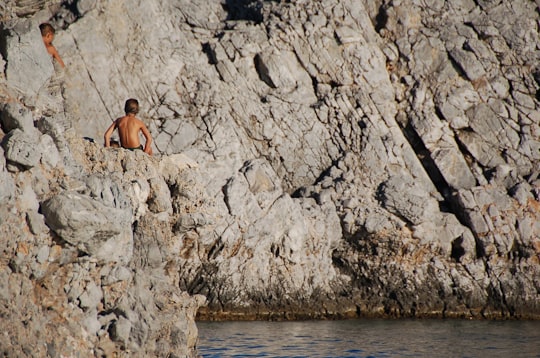person sitting on cliff in Lindos Greece