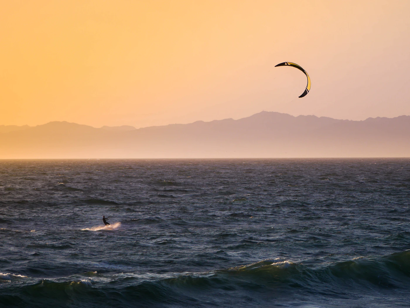 Kite surf al tramonto su spiaggia ventosa