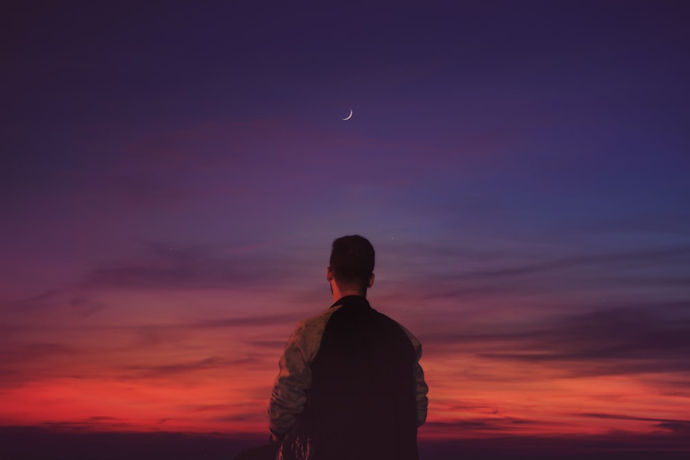 man in black jacket looking at the moon