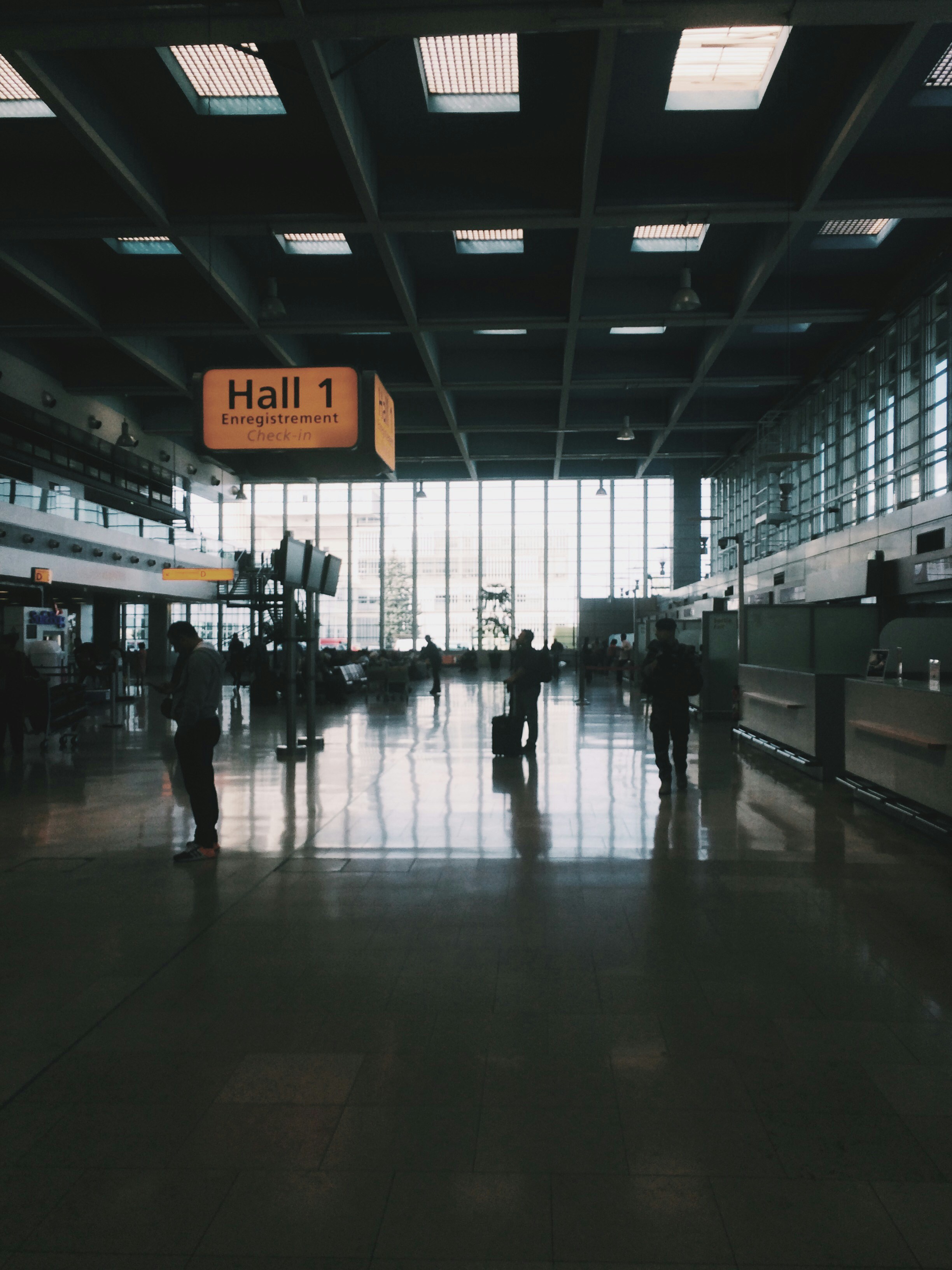 Bright, well-lit airport departure hall with travelers and large windows