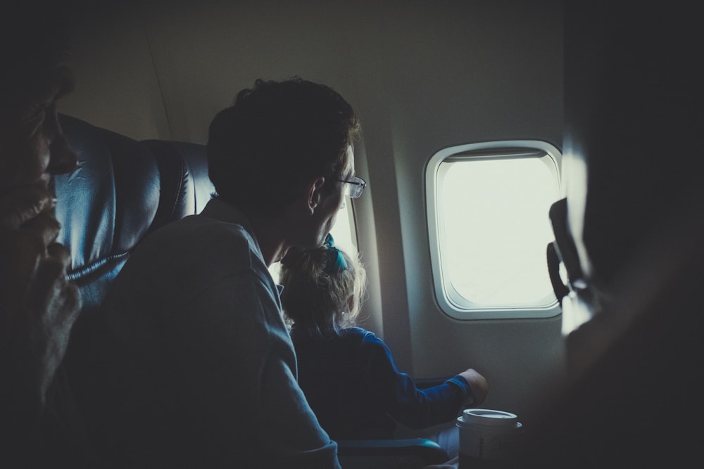 uomo e ragazza che si siedono all'interno dell'aeroplano durante il giorno
