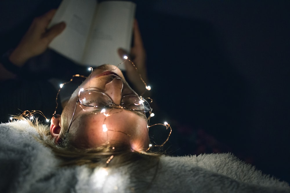 man reading book with string lights turned on