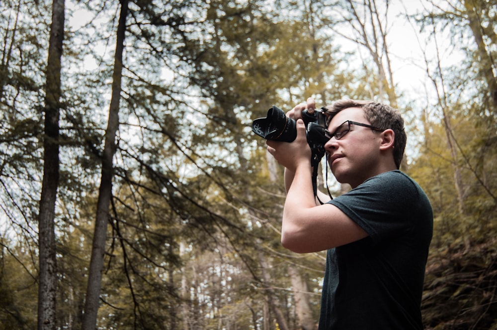 man wearing black shirt taking photo of wilderness